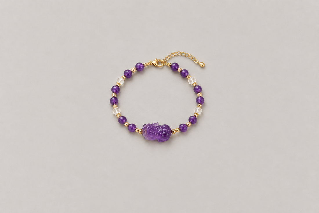 A complete purple-toned bracelet with a side-profile carved animal-like centerpiece facing left, a clasp, and an extension chain on a warm gray background