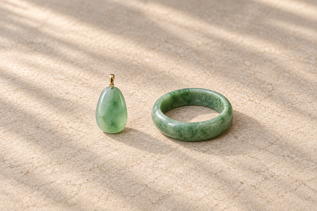 Illustrative pale green pendant and green bangle displayed side by side on a neutral stone surface