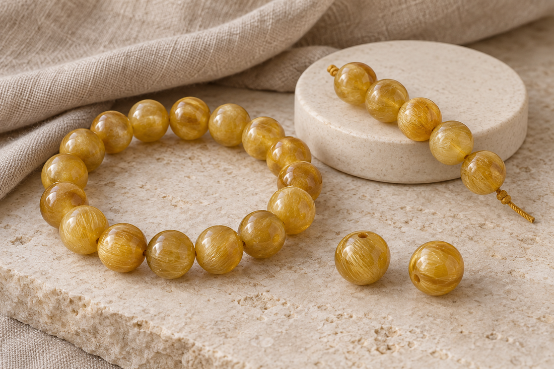 Golden-yellow beaded bracelet, loose strand, and sample beads showing varied silky patterns on pale stone.